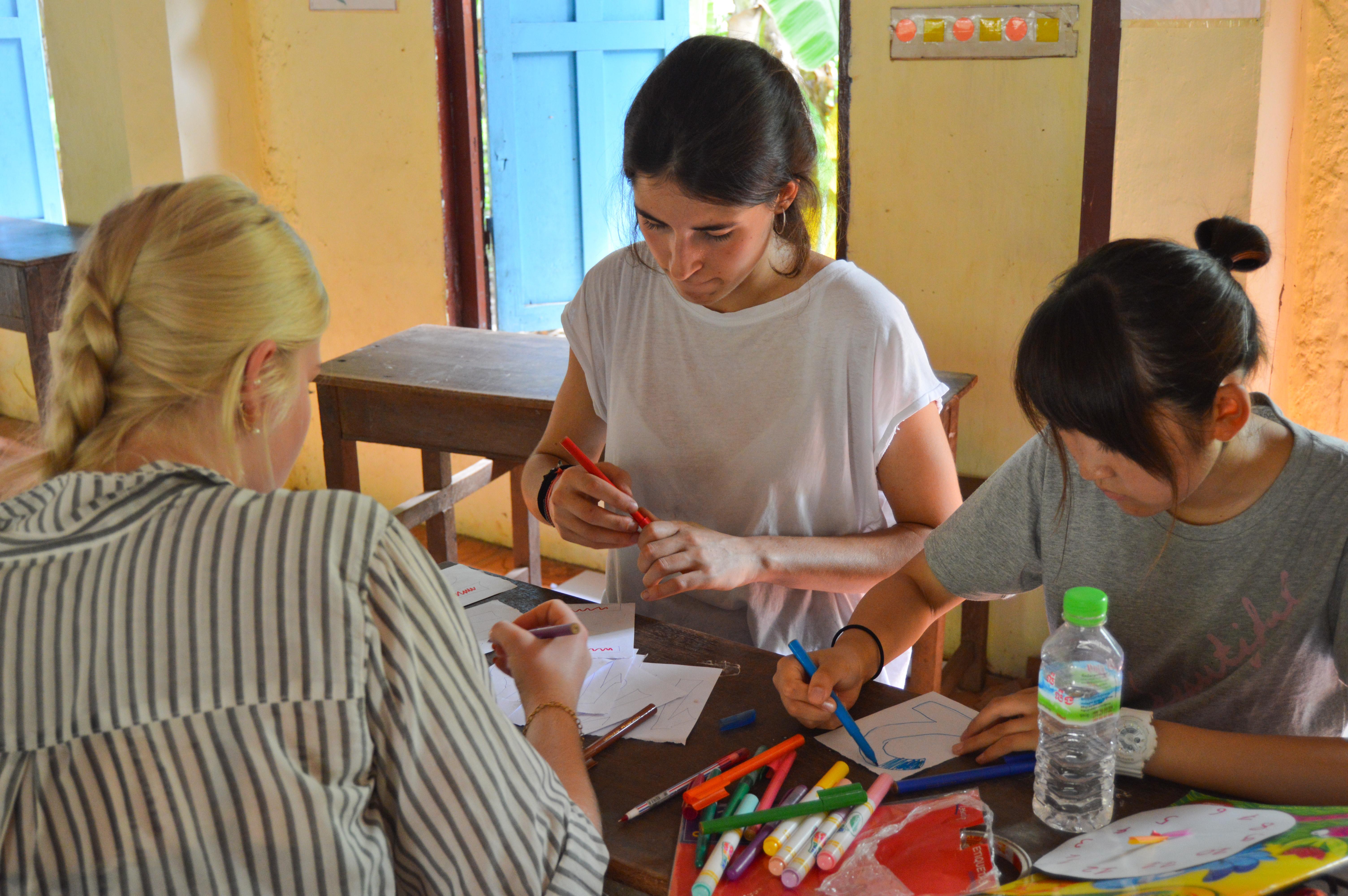As part of their Projects Abroad service learning project for middle school students in Cambodia, volunteers prepare an activity for a kindergarten class. Part of the Experiential Learning model in Cambodia for middle school students, is for students to help by preparing activities in a kindergarten.